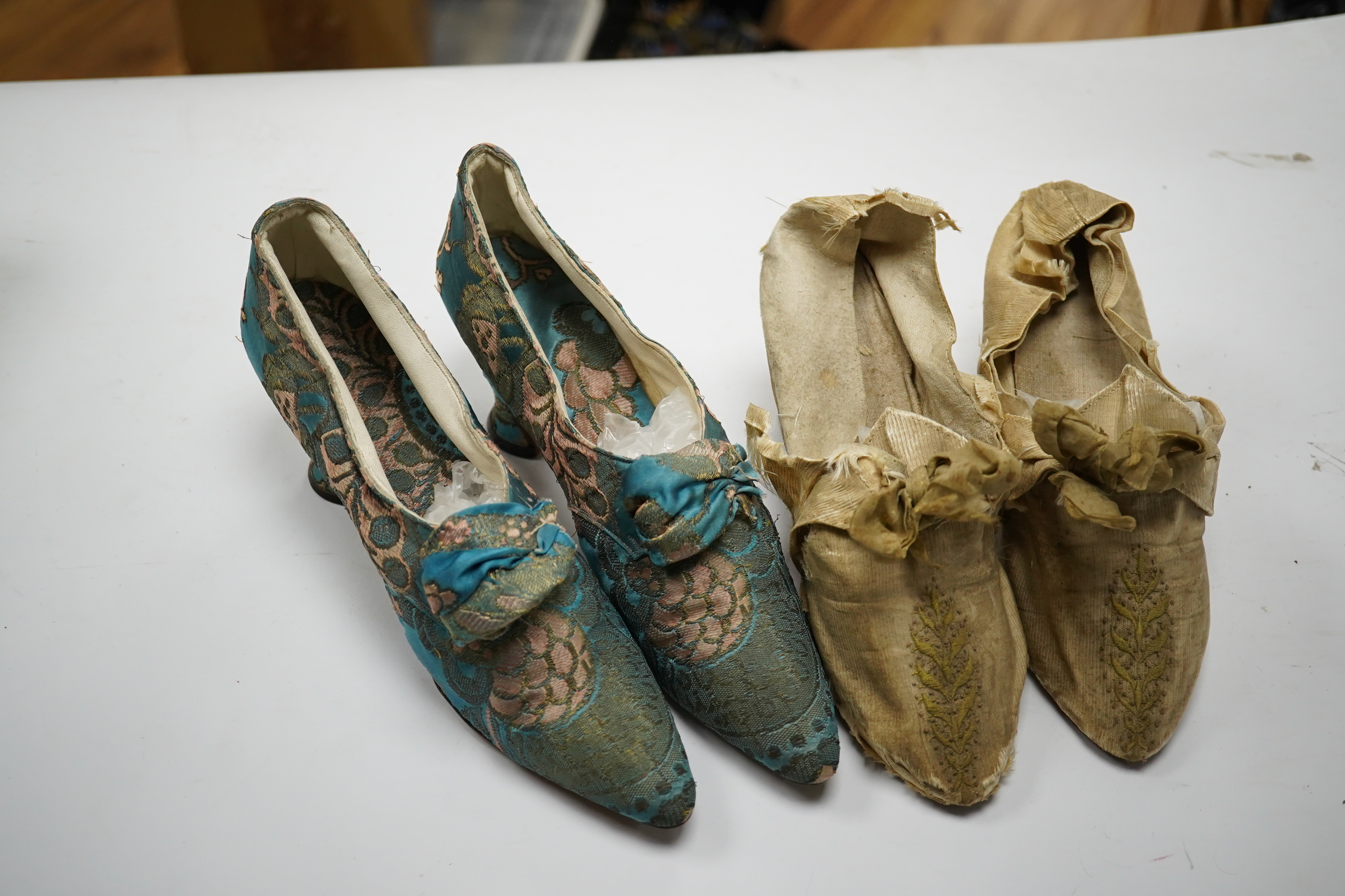 A pair of 18th century cream silk and embroidered ladies shoes together with a later 19th century silk brocade pair of ladies shoes, retailed by C. Moycopf, Burlington Arcade, both pairs lined in soft cream kid leather.